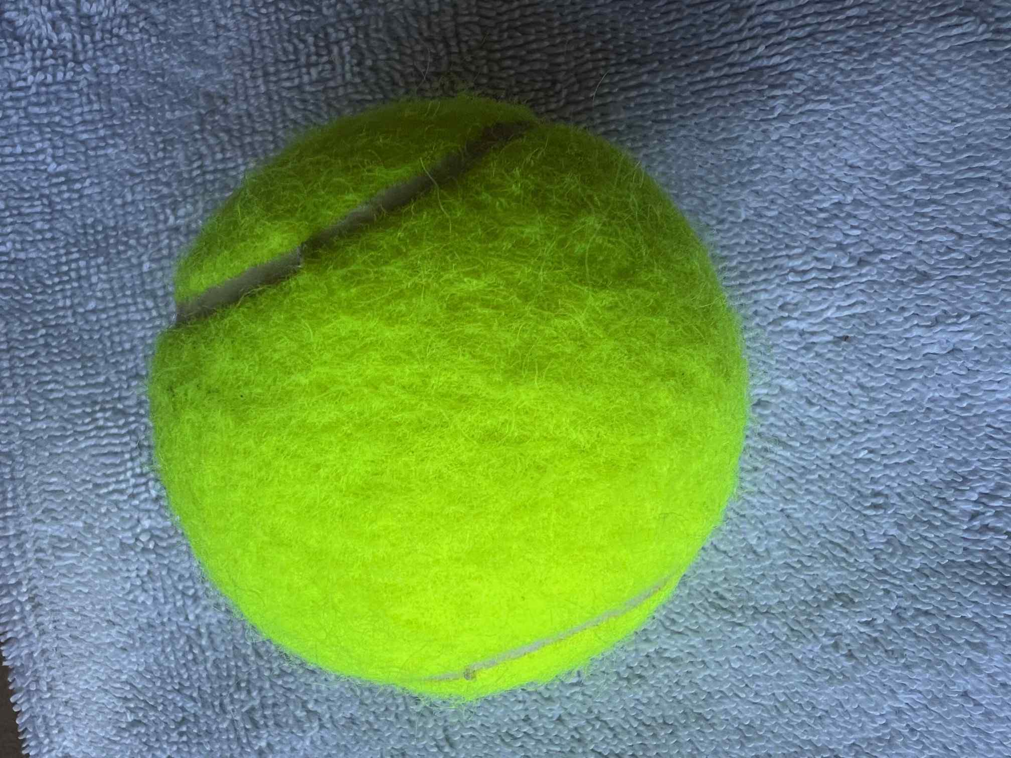 Close-up of a tennis ball showing felt texture and surface detail